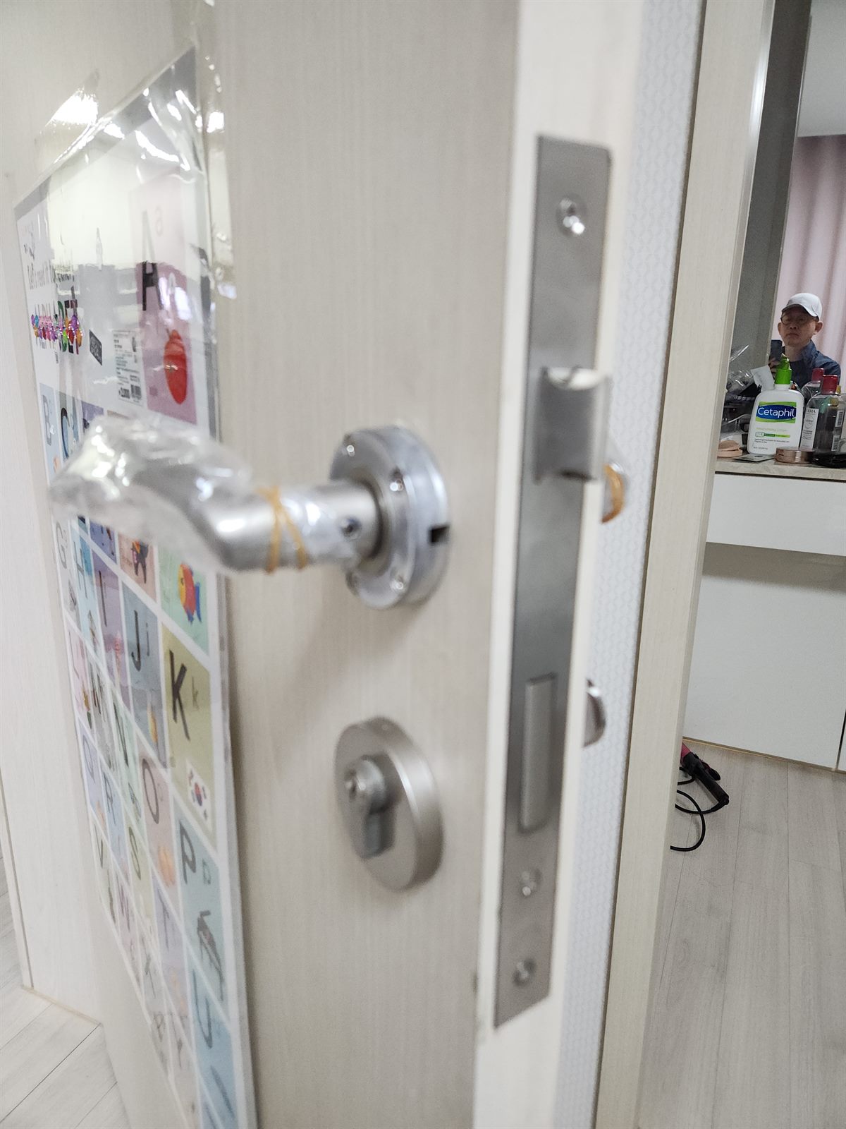 새 모티스락 손잡이 세트로 교체를 마친 문, 보호 비닐과 열쇠가 걸려 있다